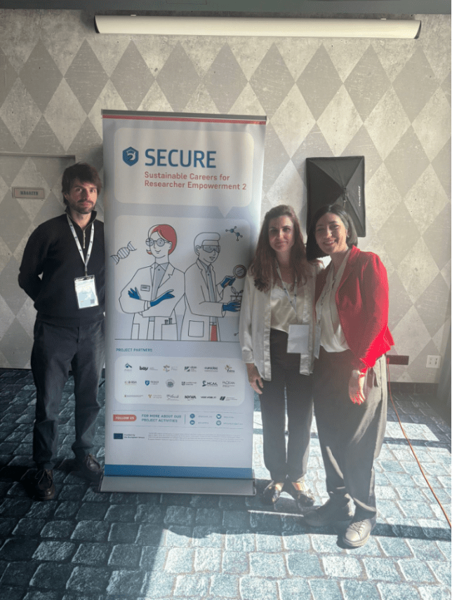 Three people standing in front of a banner titled SECURE: Sustainable Careers for Researcher Empowerment 2
